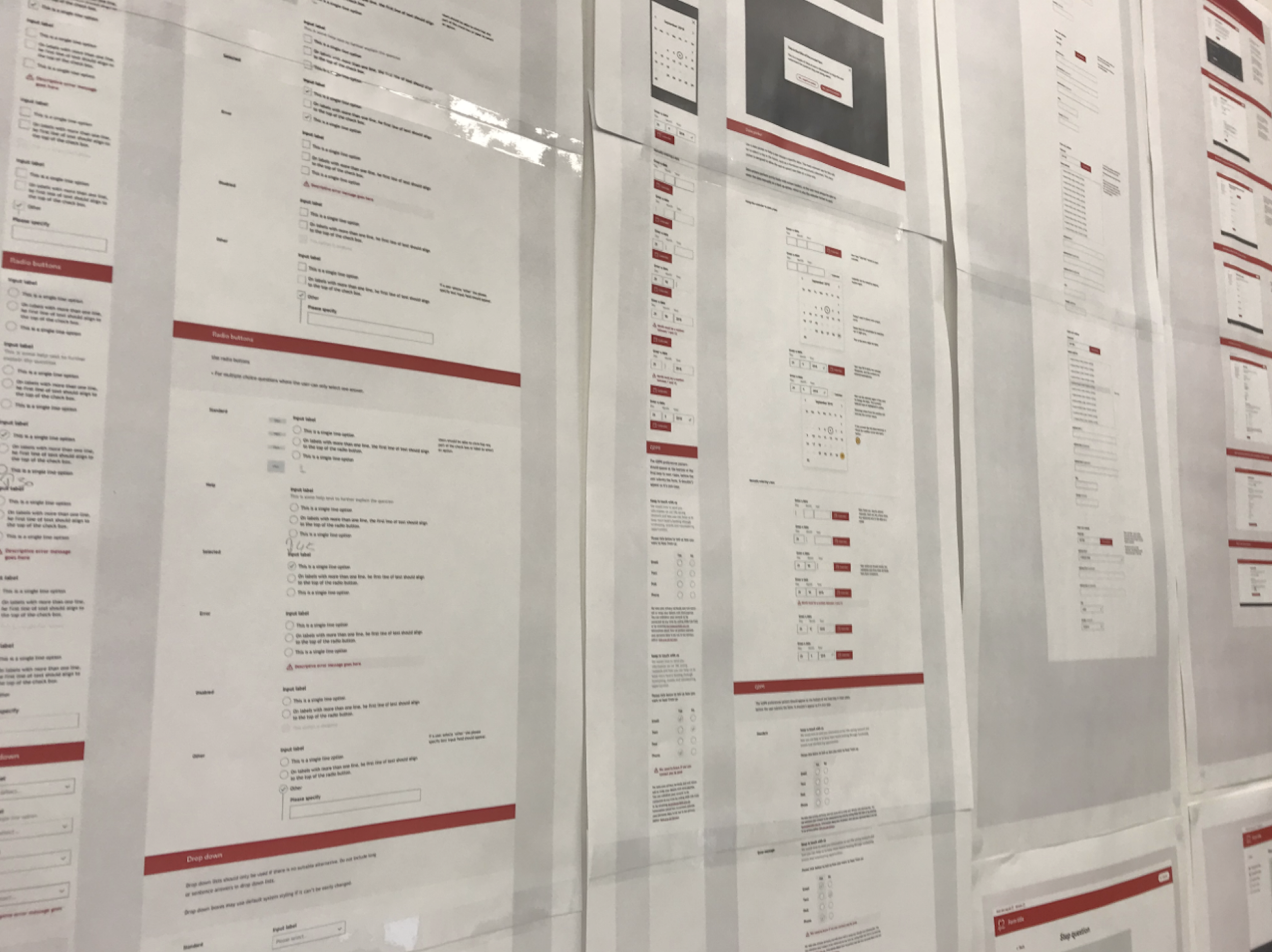 Redesigned form pages printed and pinned to a wall